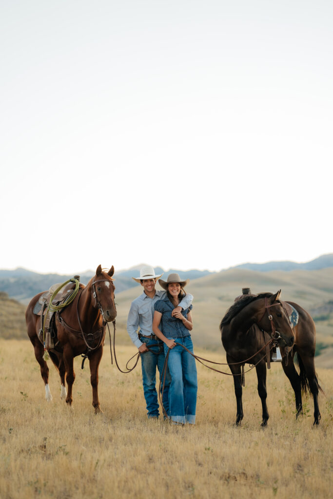 man and woman embracing and smiling with two horses