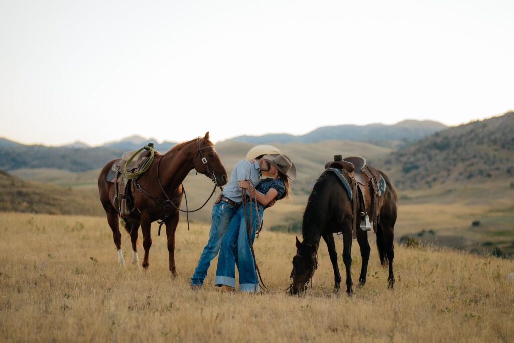 a man and woman kissing with horses on either side of them