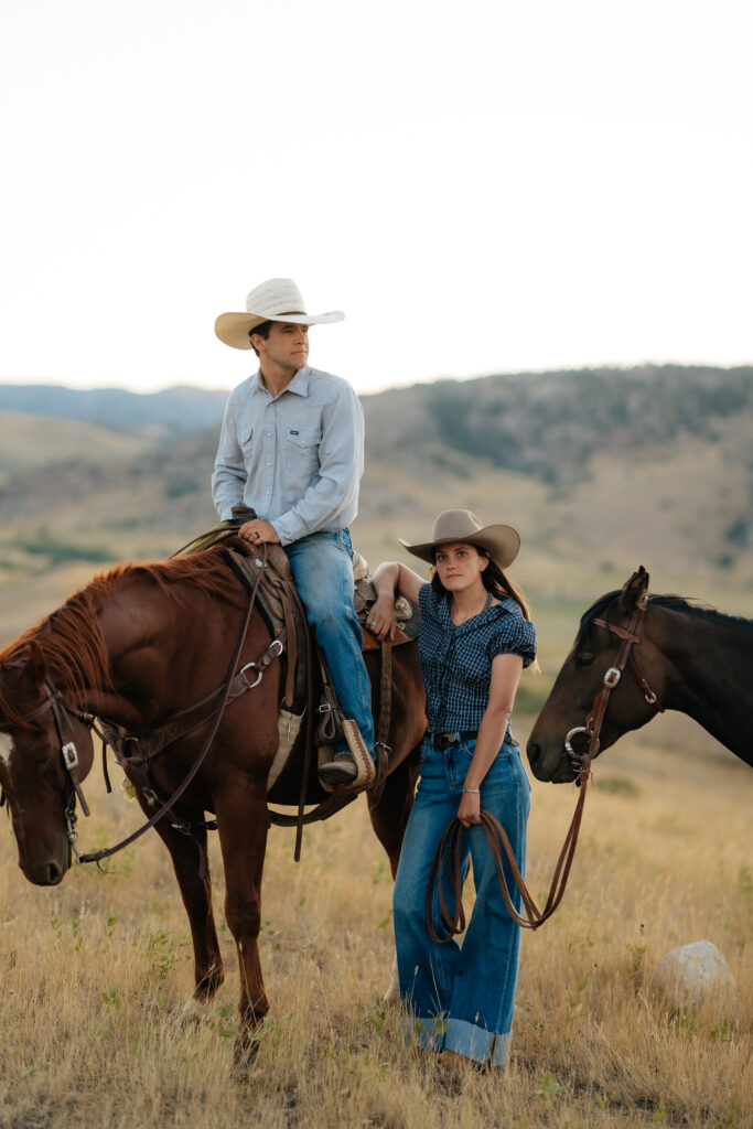 woman looking forward while leaning against a horse where a man is in the saddle looking off in the distance